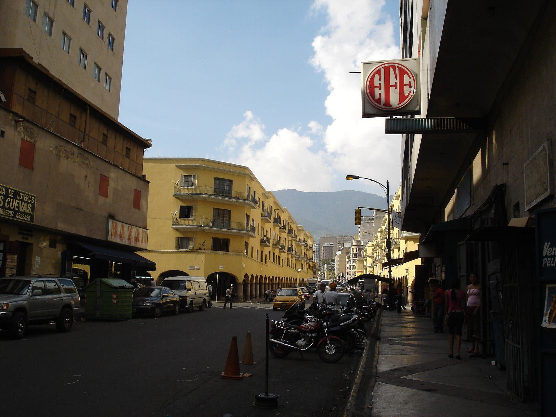 Yellow arcaded apartment blocks of El Silencio curving along a street, with mountains behind