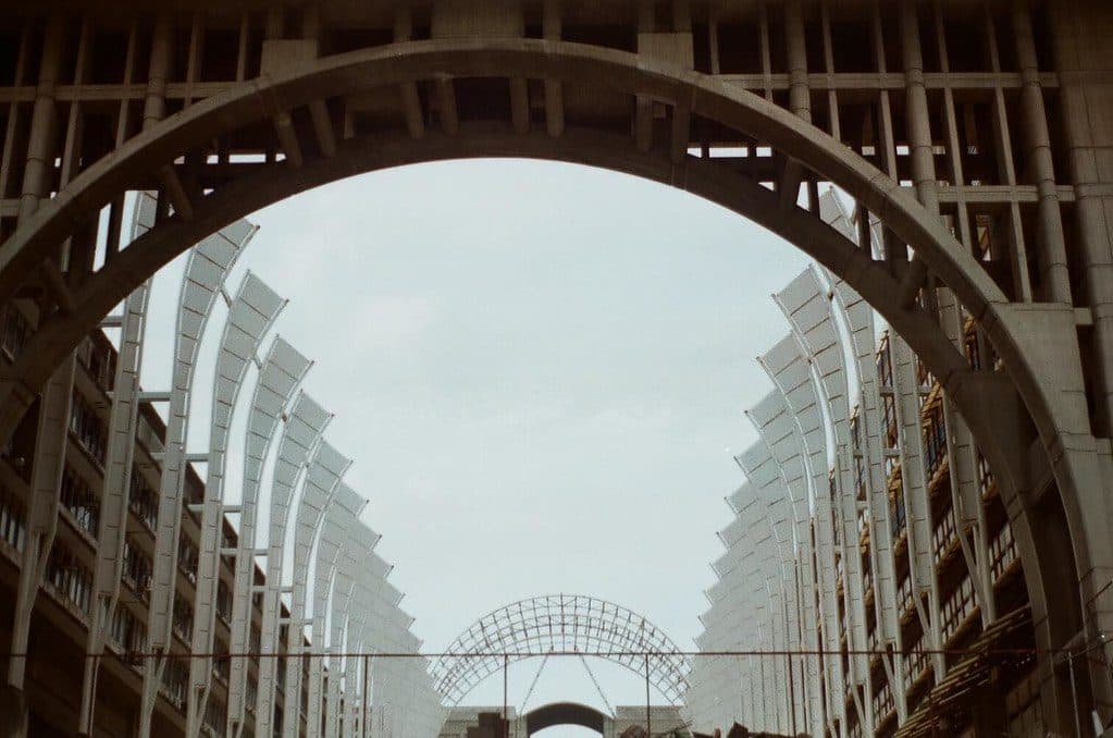 Looking up at the large concrete arch and curved glazed fins of the Palacio de Justicia complex over Avenida Bolívar, Caracas