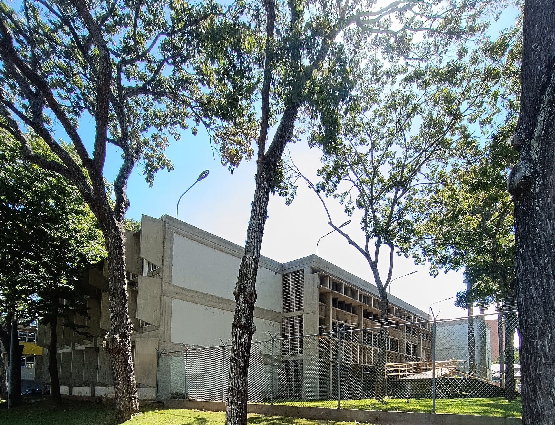 Concrete facade of the School of Sanitary Engineering at the UCV, seen through trees