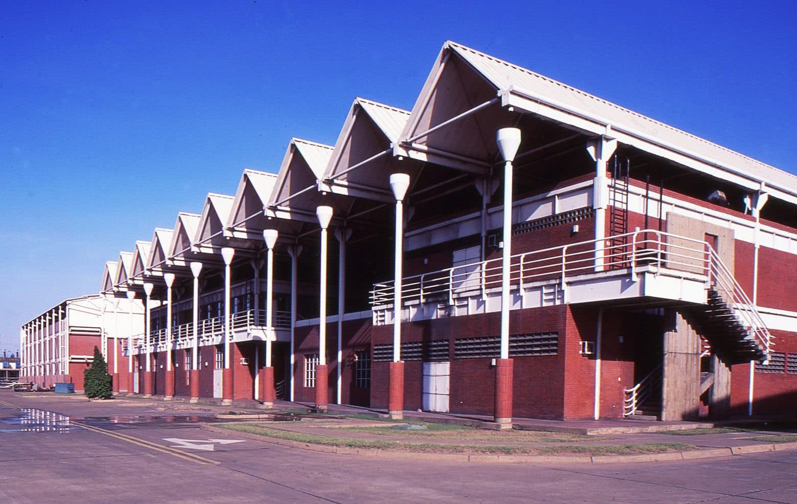 Two-storey red-brick building with a row of white gabled roofs on slender columns