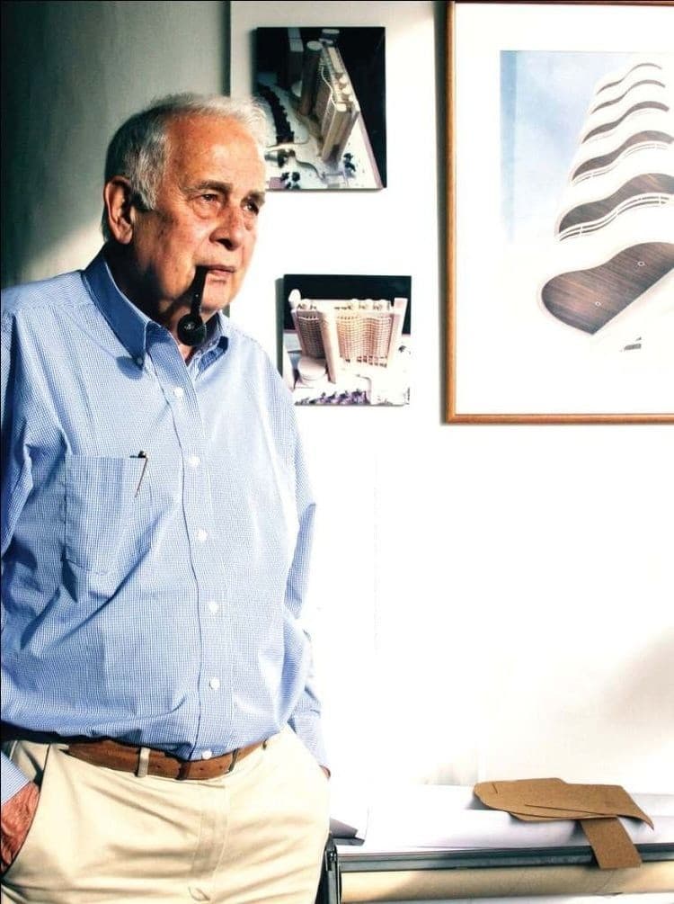 Julio Maragall in his studio, with models and a drawing of his towers on the wall behind him