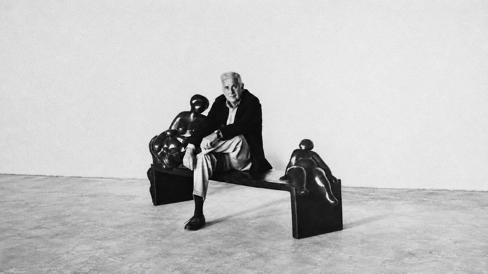 Julio Maragall seated on a bronze bench between two of his sculptures