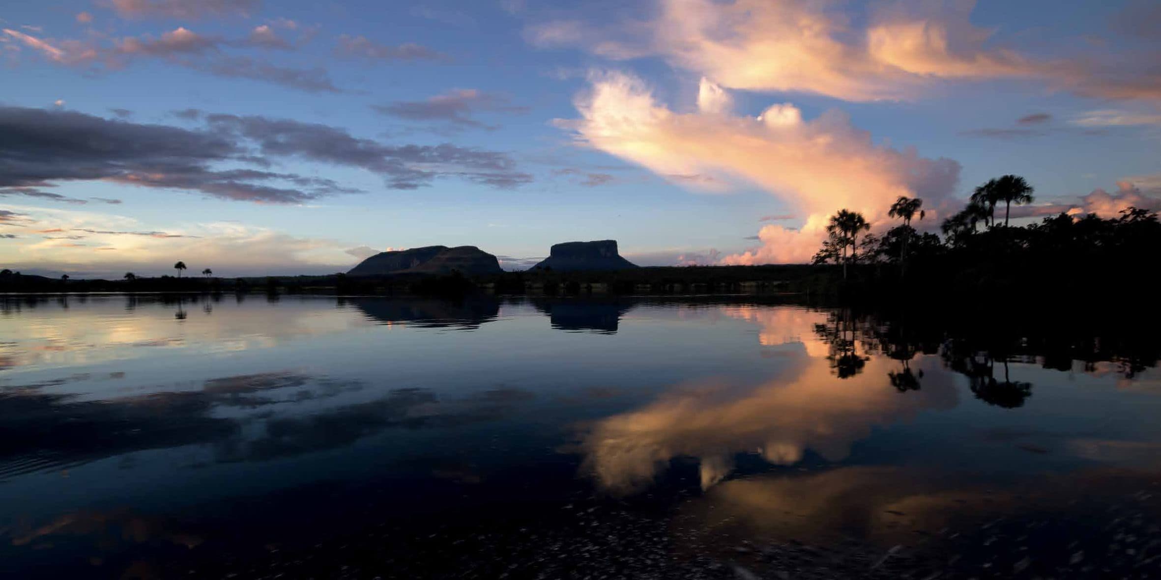 A tepui silhouetted and mirrored in still water at dusk